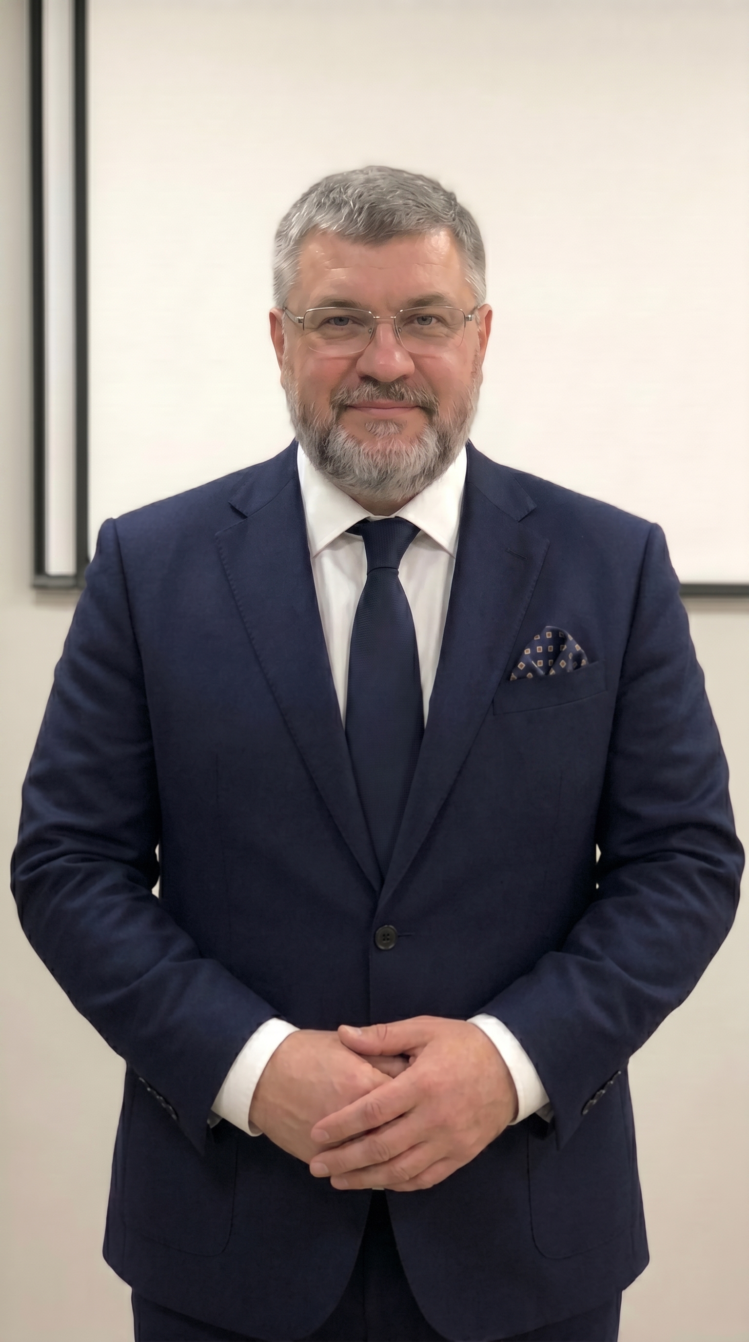 Изображен мужчина преподаватель по направлению ГО и ЧС, на заднем фоне стена и экран