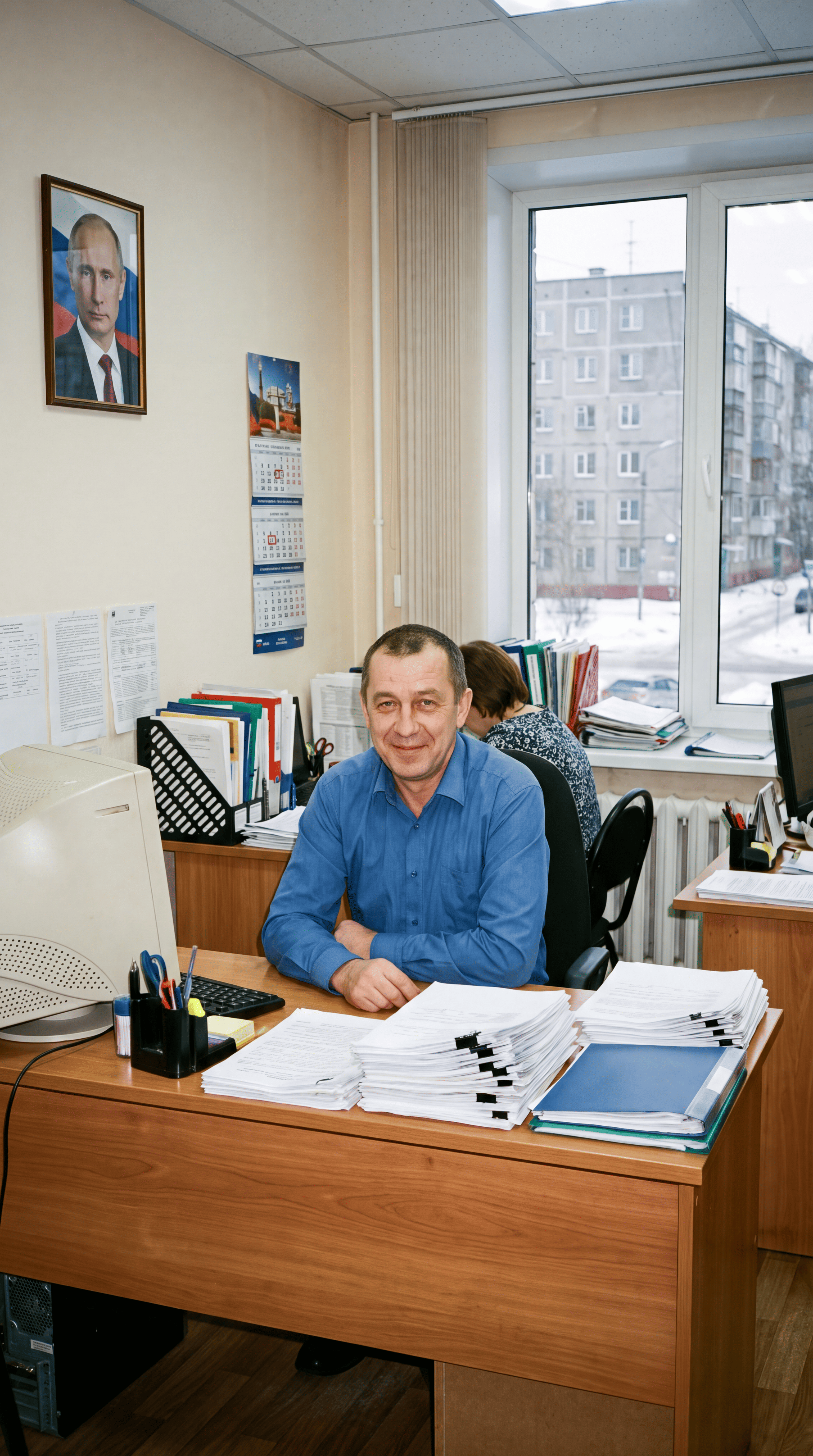 Мужчина в синей рубашке за рабочим столом с документами в офисе — отзыв слушателя курсов по информационной безопасности.